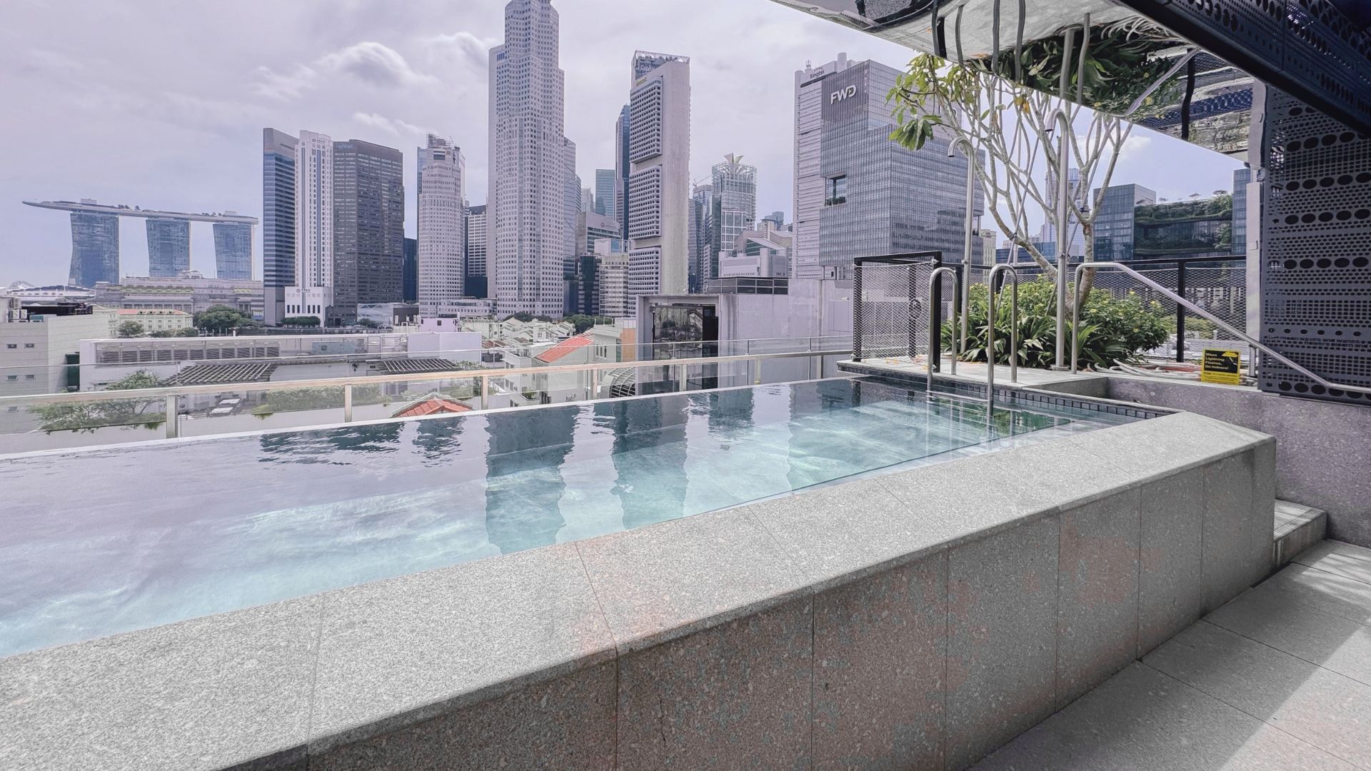 The rooftop swimming pool at 21 Carpenter hotel overlooking Singapore's cityscape. Its original finish is kept in exposed polished stainless steel, without any tile or surface cladding.