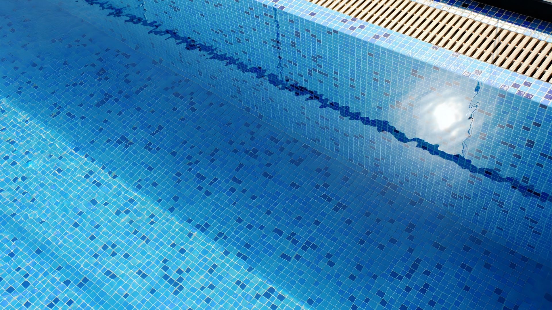Close-up of a stainless steel rooftop pool at a private landed home in Singapore. Tiles of various blue shades line the pool walls.
