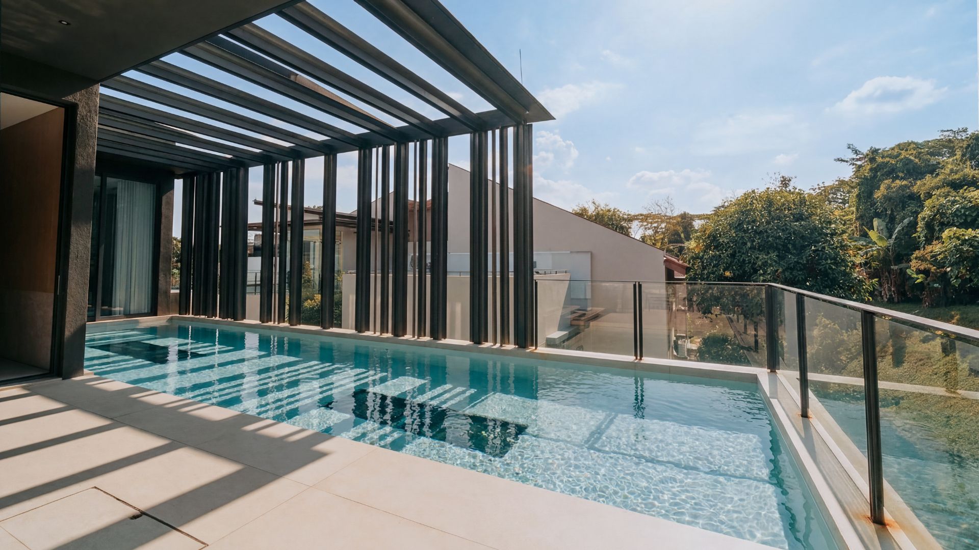 Stainless steel outdoor rooftop pool at a private landed home in Singapore, with underwater window sections on the pool floor. A fancy wooden architectural enclosure shades part of the pool, which permits sunlight to stream through in between gaps.
