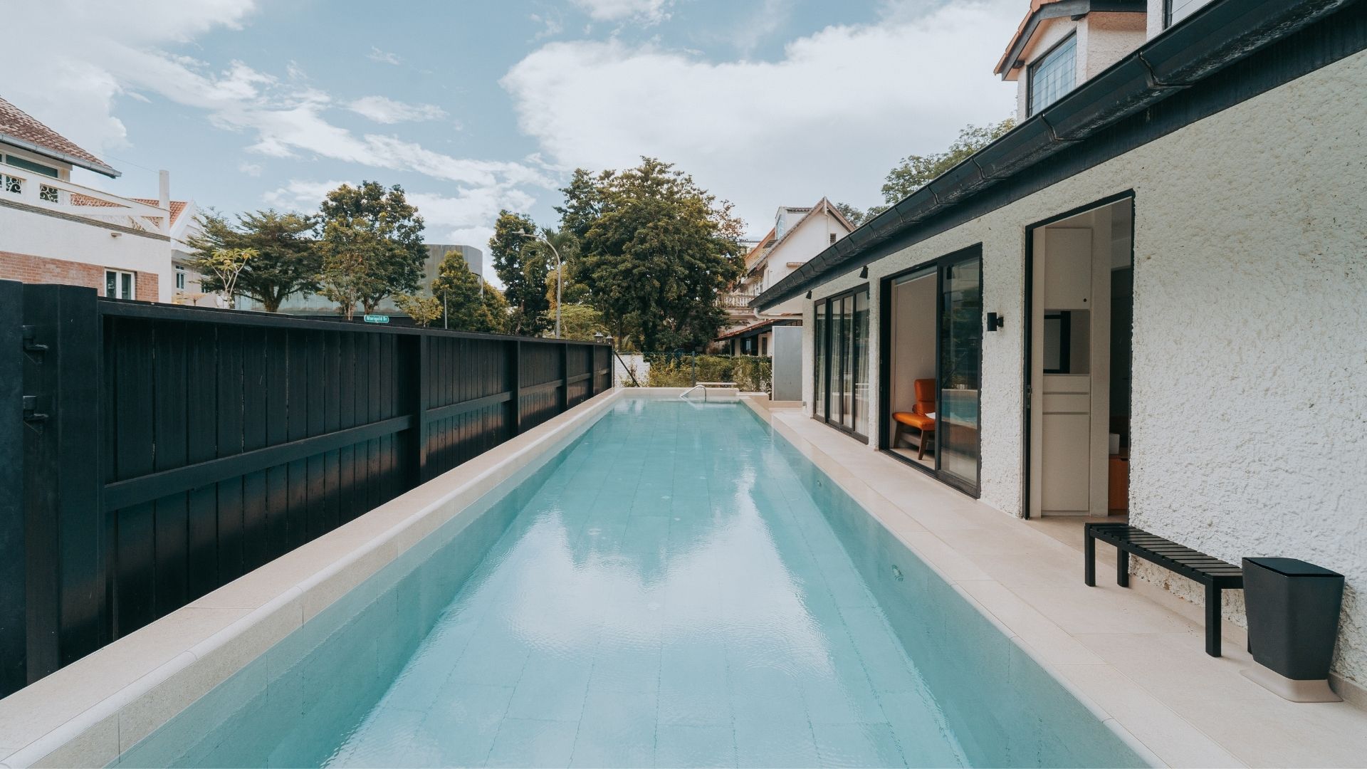 A newly-built 13.5 metre concrete swimming pool at the front porch of a private landed home in Singapore, wide open to the sky.