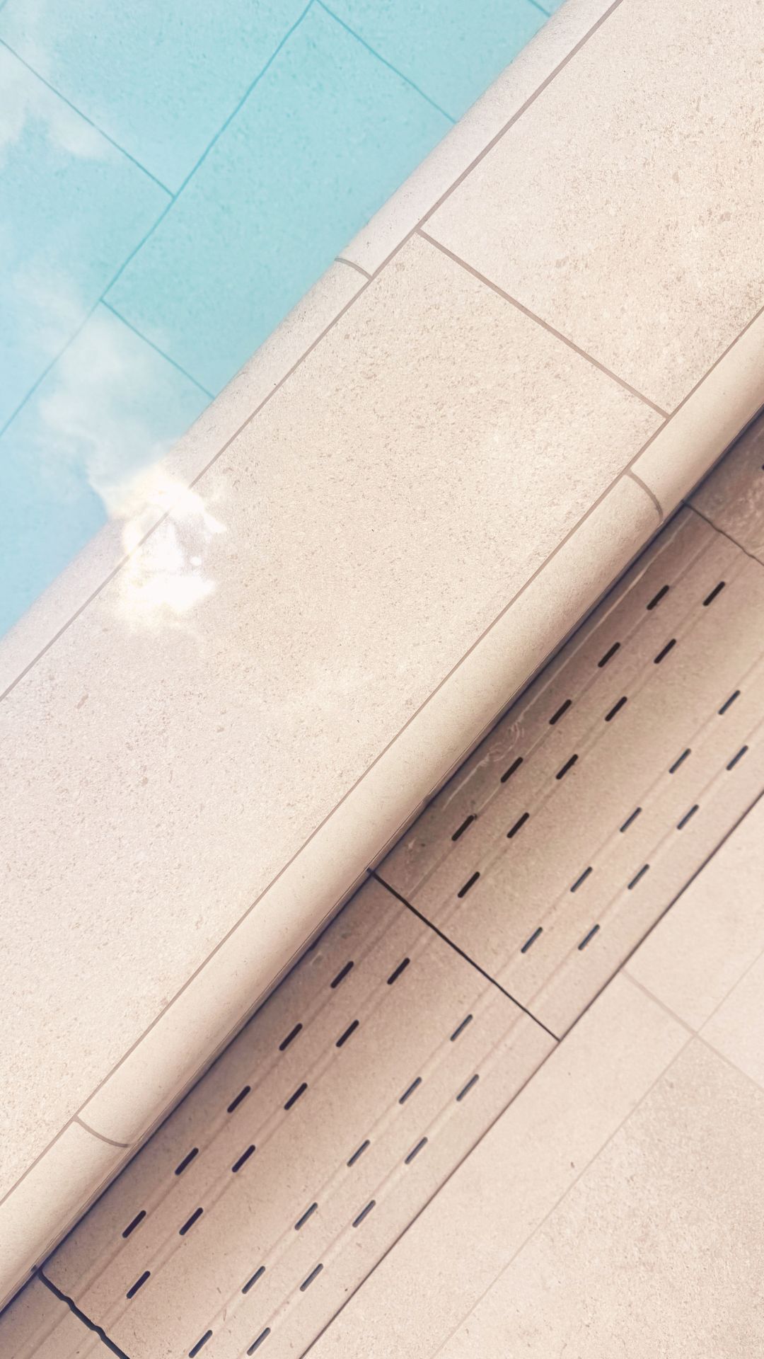 Close-up of the concrete swimming pool, its stepped edge and gutter, at a private landed home in Singapore. The tiling comprises of Spanish porcelain tiles in neutral tones for aesthetic purposes.