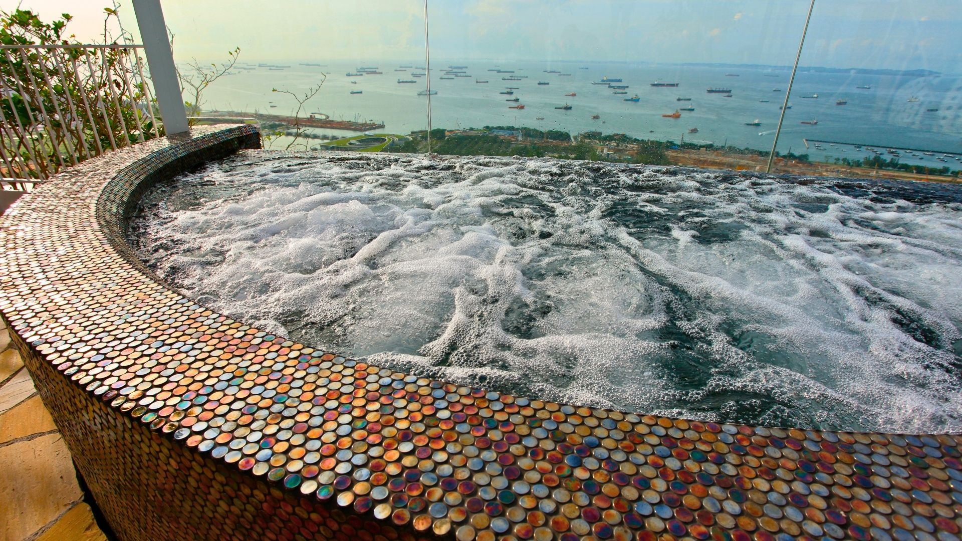 Close-up of the stainless steel spa tub at Marina Bay Sands (MBS) in Singapore. The tub is made up of colourful, iridescent round mosaic tiles. Ships appear as specks in the distance.