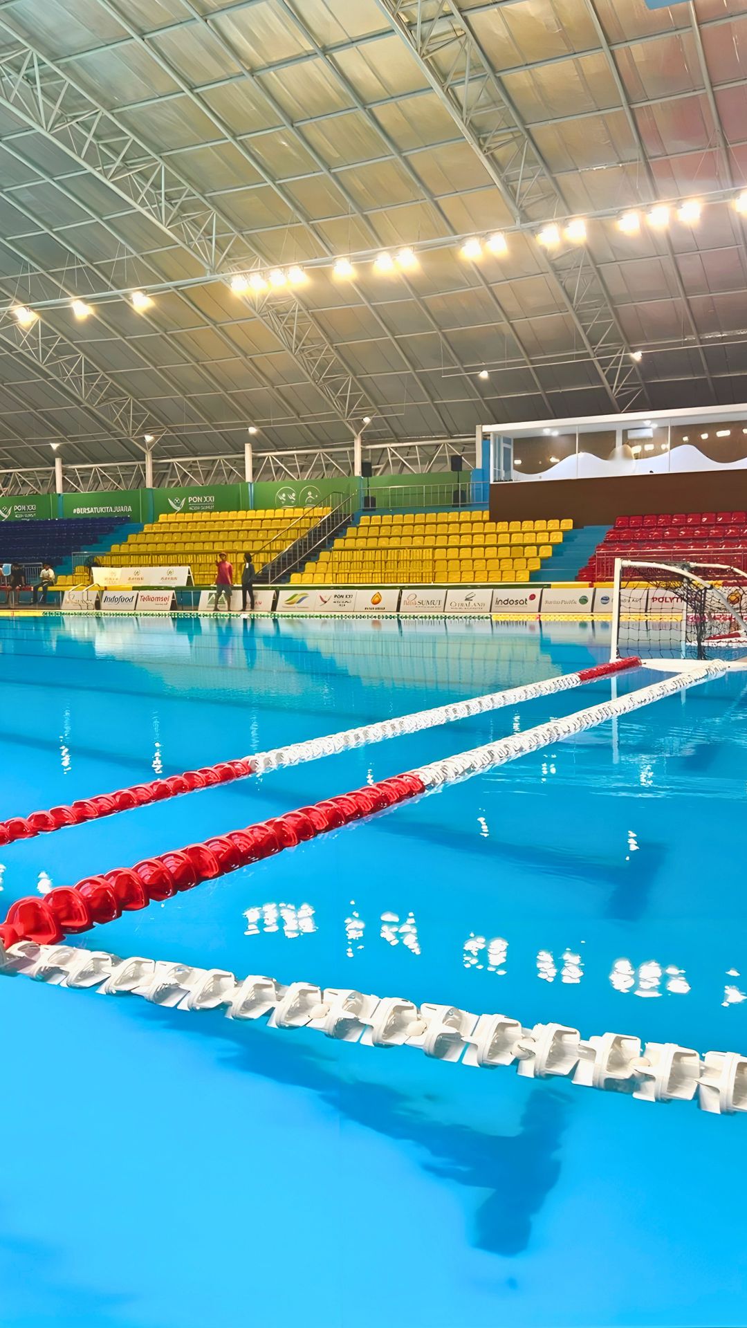 Close-up of thick, sturdy swimming pool ropes at the Selayang Aquatic Centre. Bright yellow and red spectator seats are empty in the background.