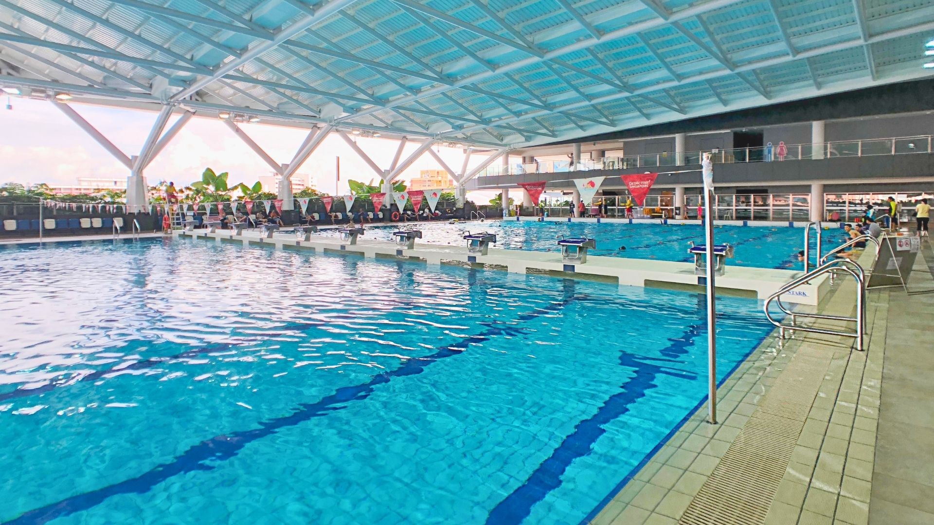 Close-up of the bulkheads at Our Tampines Hub Swimming Complex, with metallic starting blocks fixed on top. The bulkheads split the training and competition pools up in a clear divide.