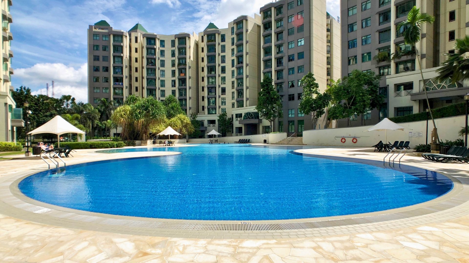 Close-up of the rounded edge of the swimming pool at Signature Park, Singapore. The pool gutter follows the curve, and pool ladders are on opposite sides. The pool deck area is wide and spacious.