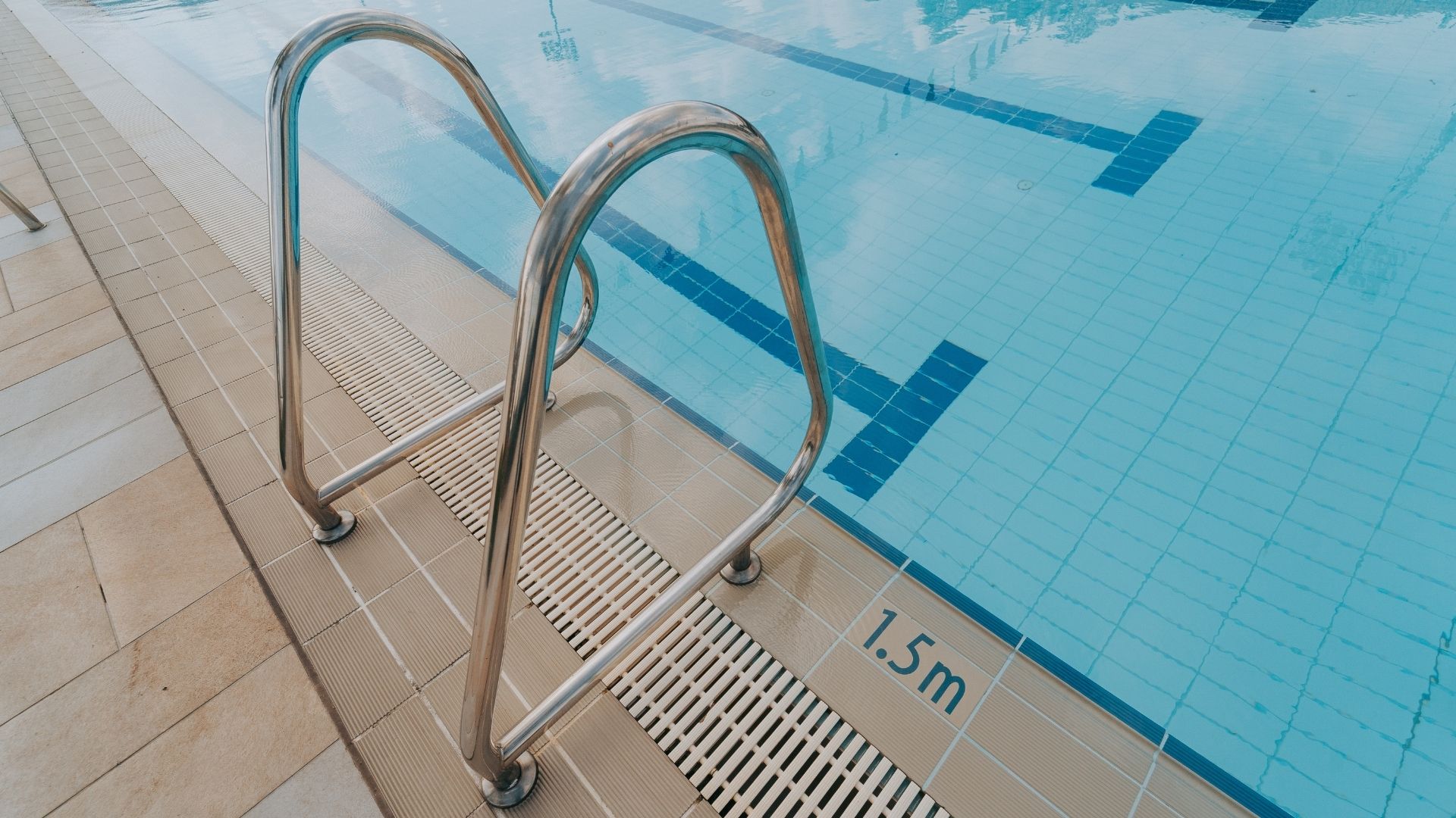 Close-up of the grab rails at the Singapore Island Country Club, which spans across the PVC drain grating. The pool depth, 1.5 metres, is printed on the German Agrob Buchtal tile beside it.