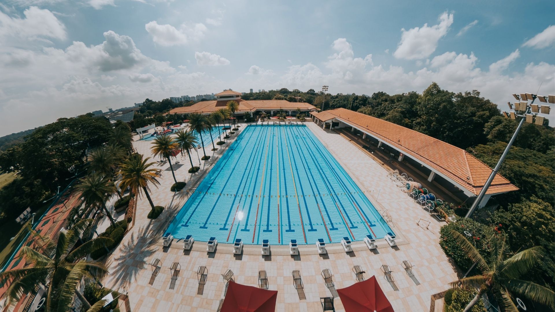 Aerial view of the competition swimming pool at Singapore Island Country Club, after upgrade works have been done. The pool looks well-equipped with various pool equipment and accessories. The children's wet playground is situated next to it.