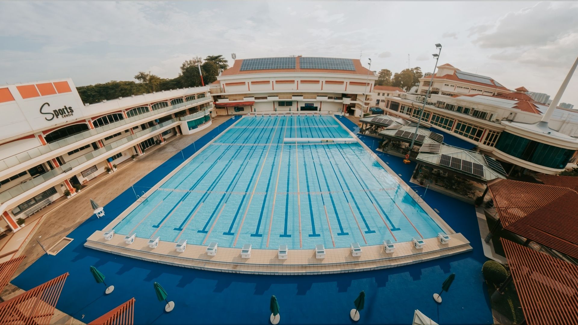 Aerial view of the largest Olympic-sized pool in Singapore, within the compounds of the Singapore Swimming Club. Comprising 12 lanes with starting blocks and flags, it stands ready for competitive swimming and water sports to take place in.