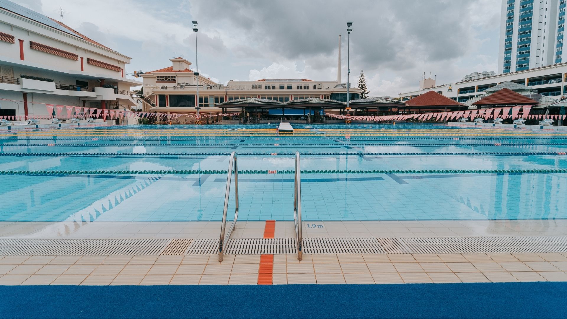 Close-up view of the grab rails along the length of the competition pool at the Singapore Swimming Club. The pool depth, 1.9 metres, is printed on a tile on the ground.
