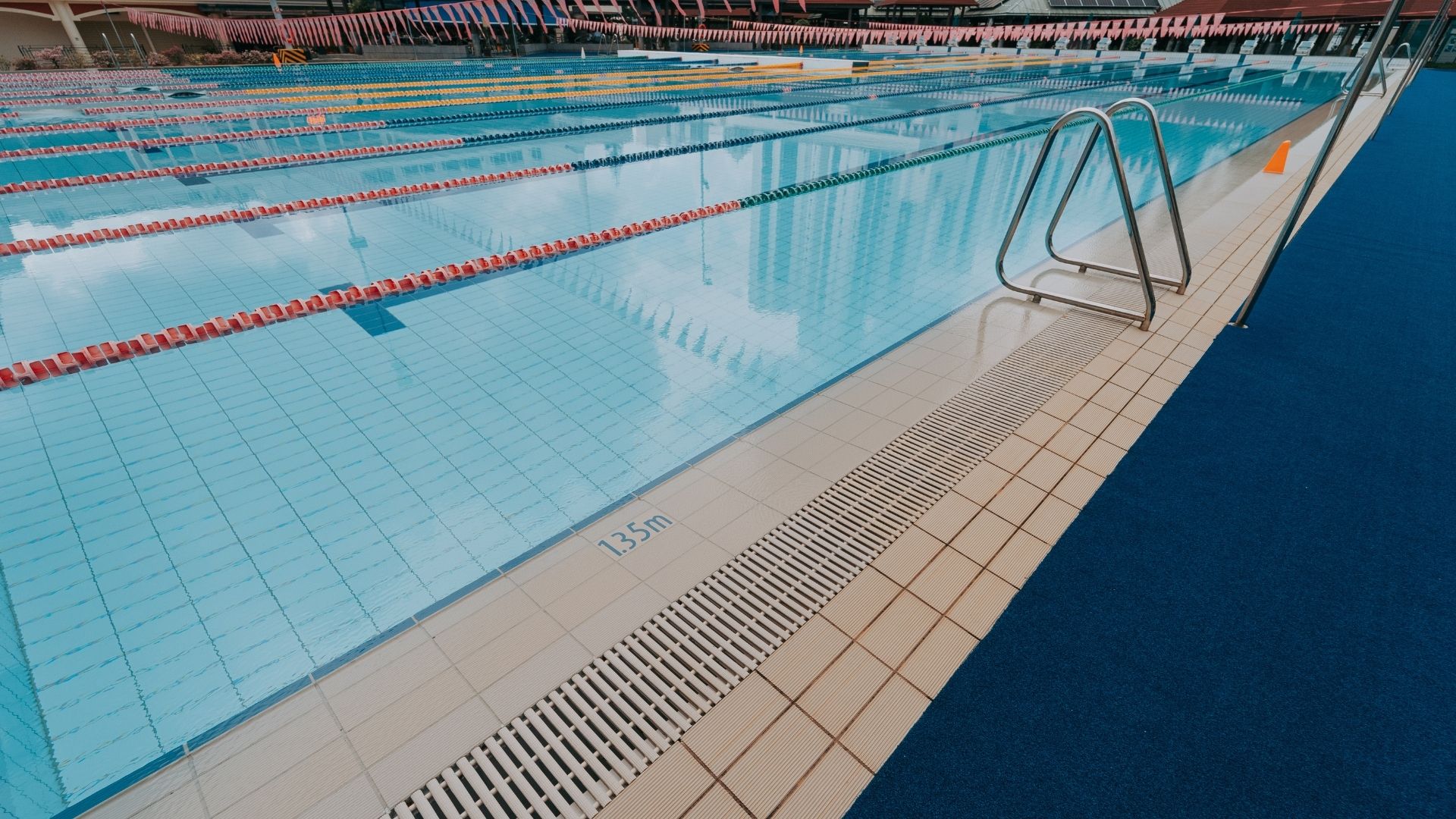 Close-up view of the grab rails and gutter of the swimming pool at the Singapore Swimming Club. The tiles look new, and the pool depth (1.35 metres) is printed on a German Agrob Buchtal tile.