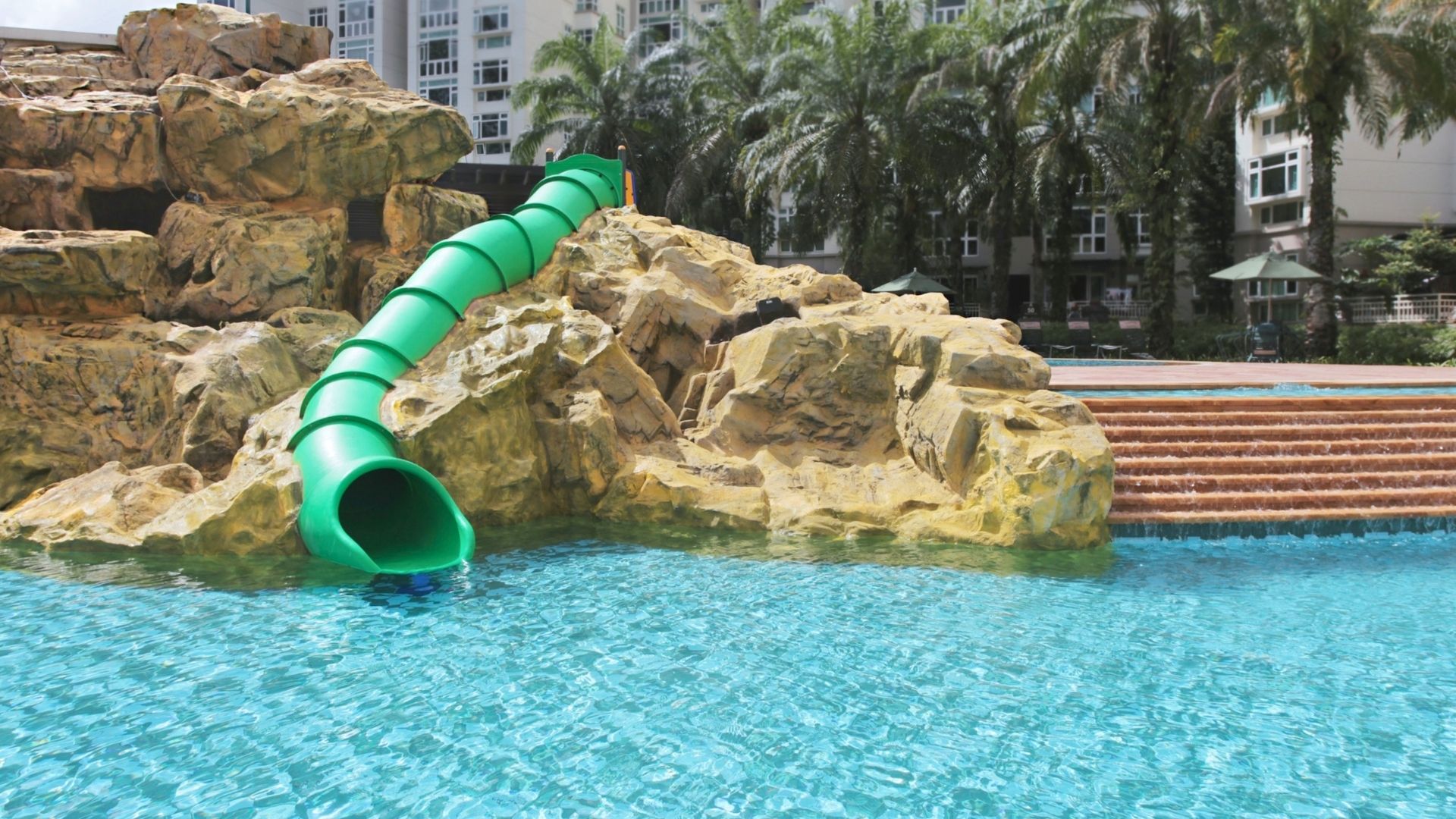 The bright green tube slide at Summerhill condominium in Singapore. It is built firmly into a well-carved rock landscape.