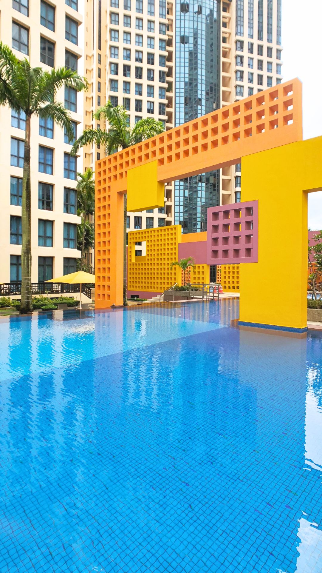 Portrait view of the swimming pool at Tanglin View Condominium in Singapore, with its unique architectural design comprising geometric square and rectangle blocks in orange and yellow.