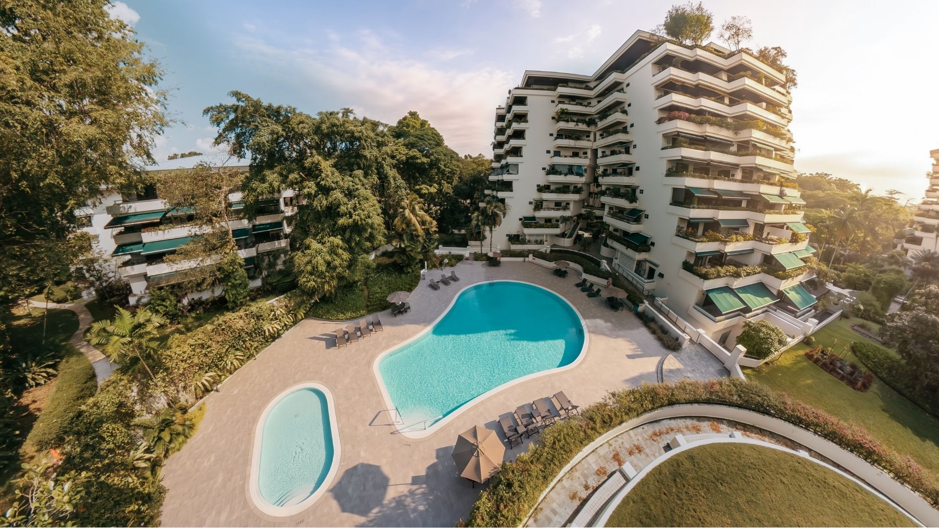 Bird's eye view of The Arcadia Condominium in Singapore, which has a resort-style feel with the lush greenery, white apartment blocks curved upwards, and two curvaceouos swimming pools with a spacious pool deck.
