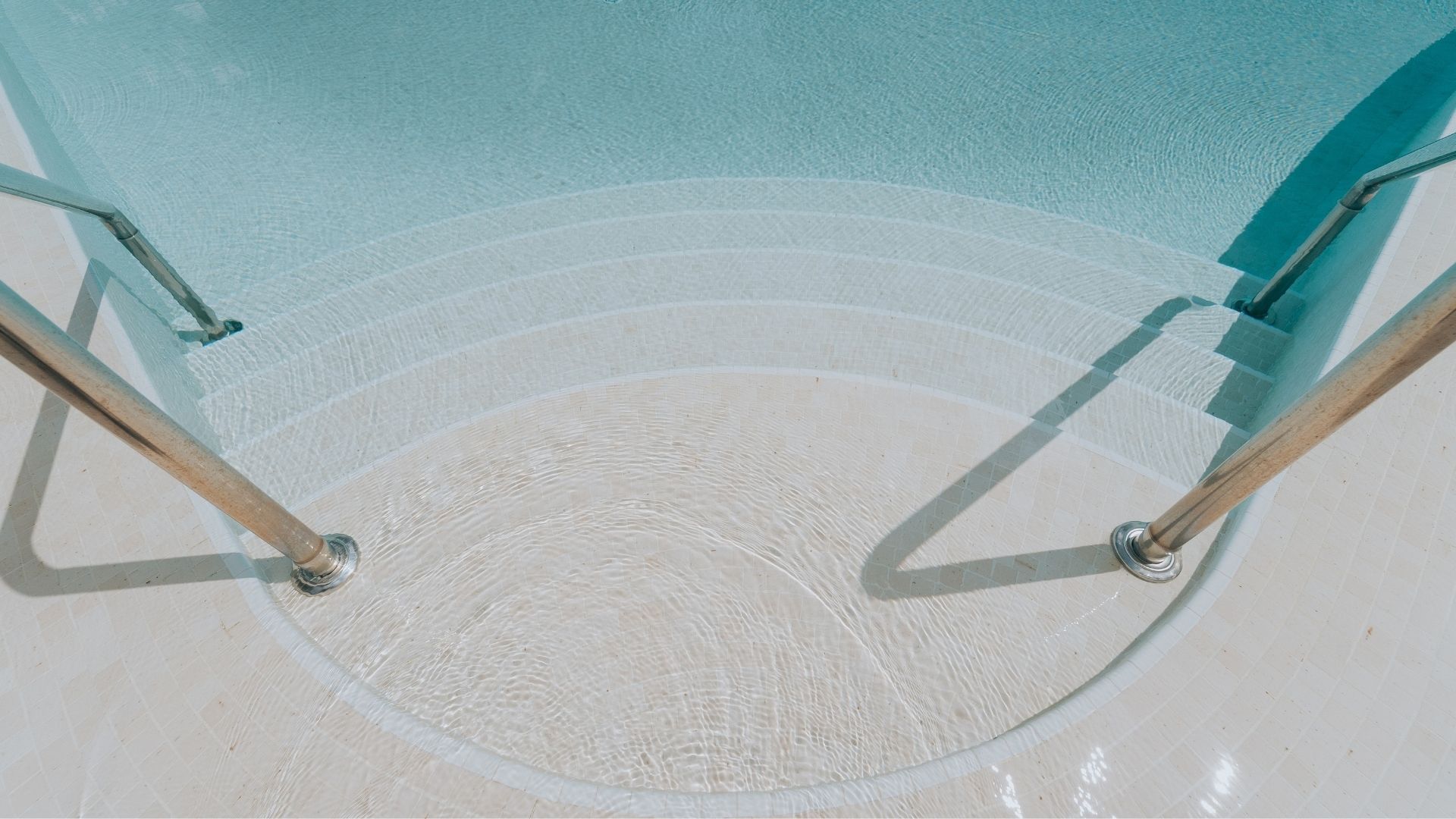 Close-up of the swimming pool steps at The Arcadia, Singapore, which lead down to the pool in graceful arcs. They are made up of cream-coloured Spanish tiles, and the pool features Spanish glass mosaic finishes.
