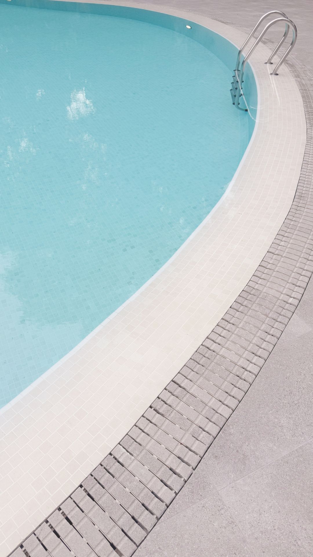 Close-up portrait of the swimming pool at The Arcadia Condominium in Singapore, featuring upgraded Spanish glass mosaic finishes, with a Spanish porcelain-tiled deck and matching porcelain tile gratings.