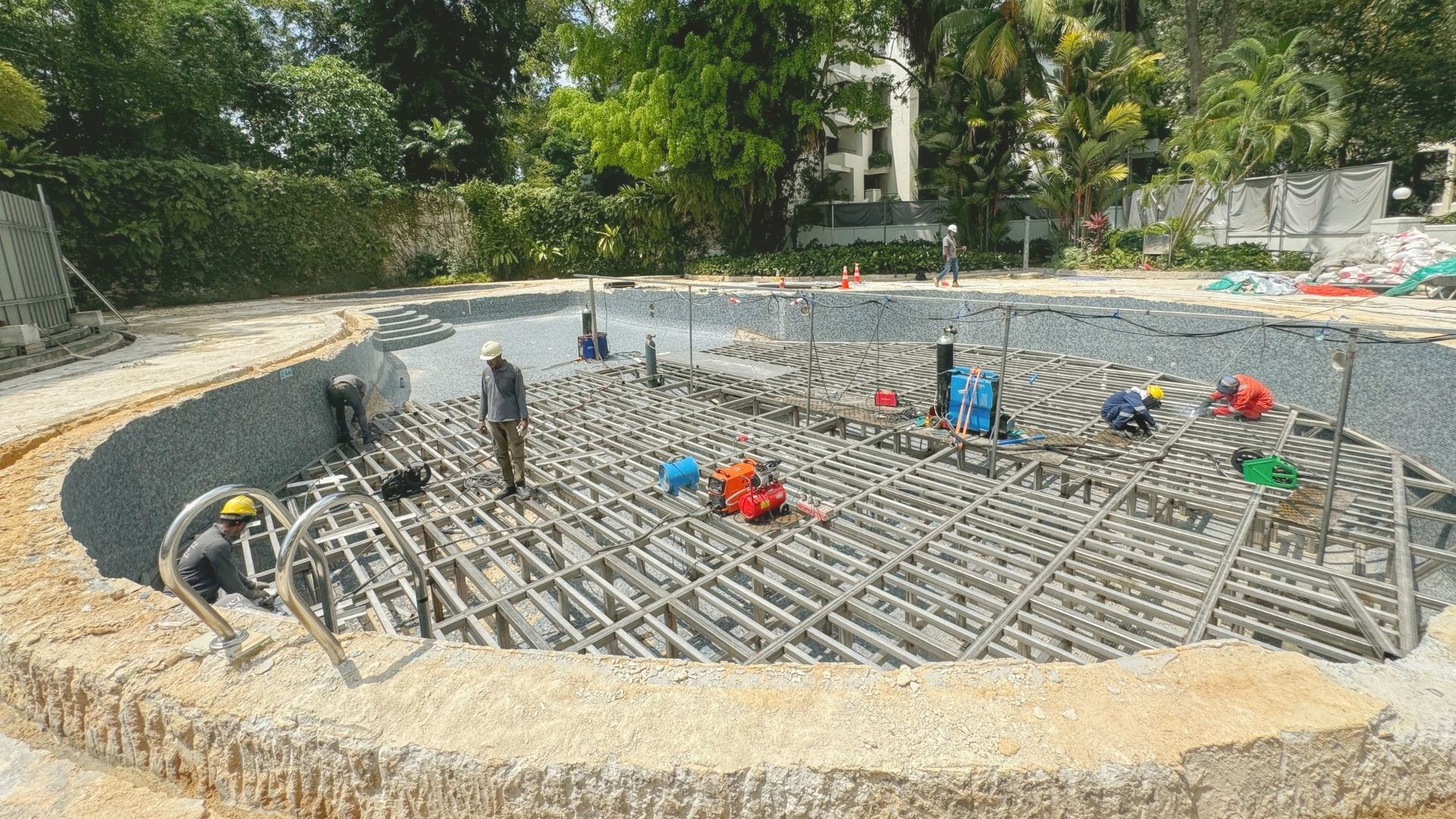 Construction workers from Innovez Engineering are spread out on top of a stainless steel structure, and are working to raise the depth of the swimming pool at The Arcadia Condominium in Singapore.