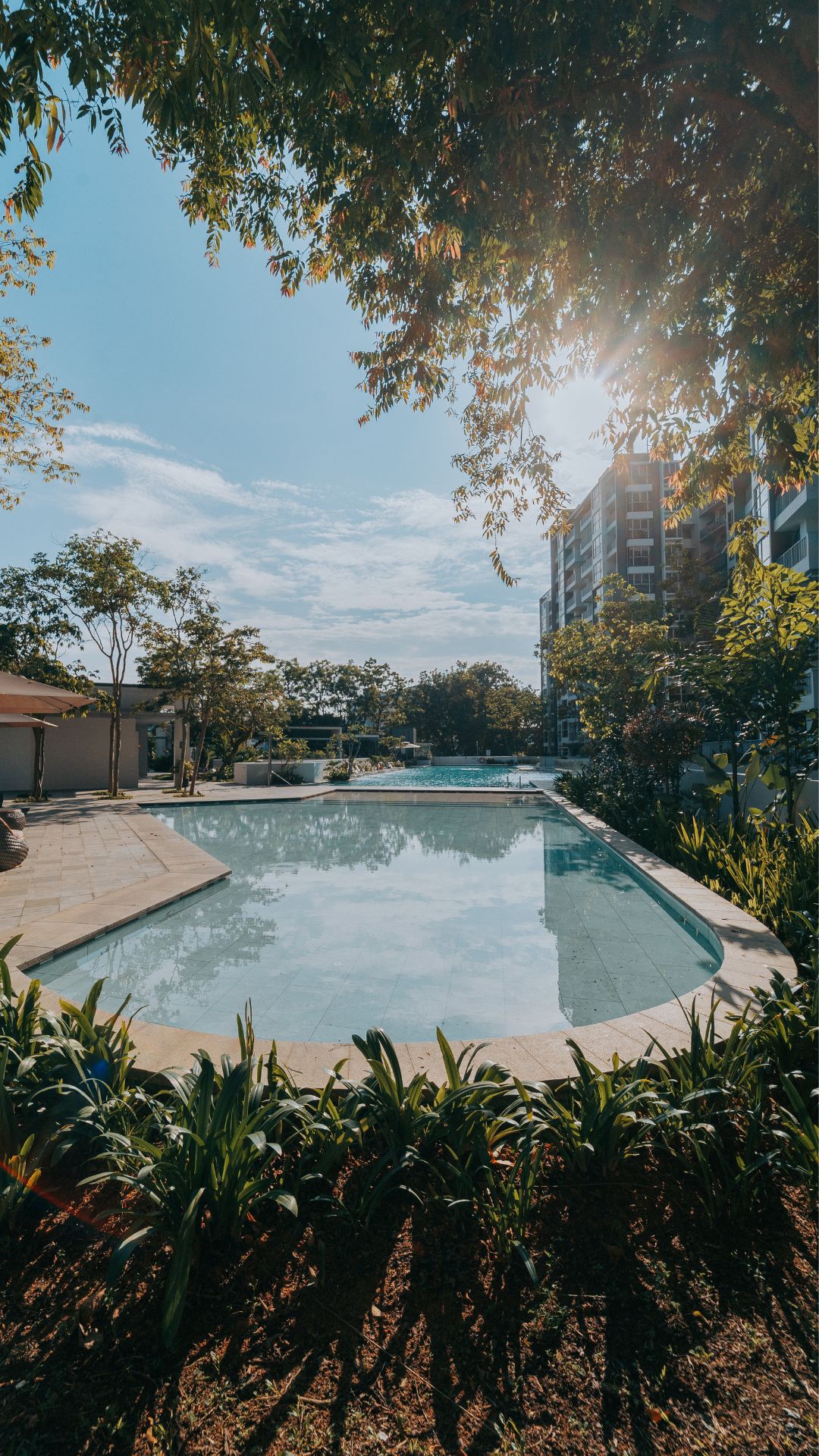 Ground-level portrait view of children's wading pool at The Estuary Condominium in Singapore, surrounded by lush greenery.