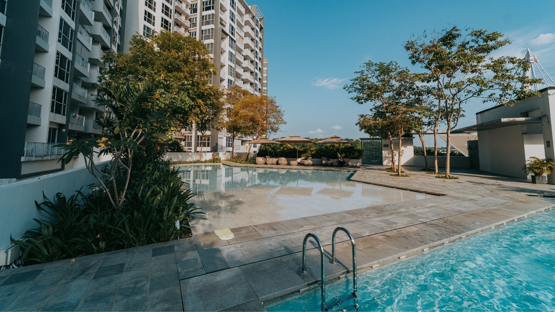 The swimming pool facilities at The Estuary Condominium in Singapore, after renovation works have been completed. A well-tiled walkway divides the main lap pool and children's wading pool.