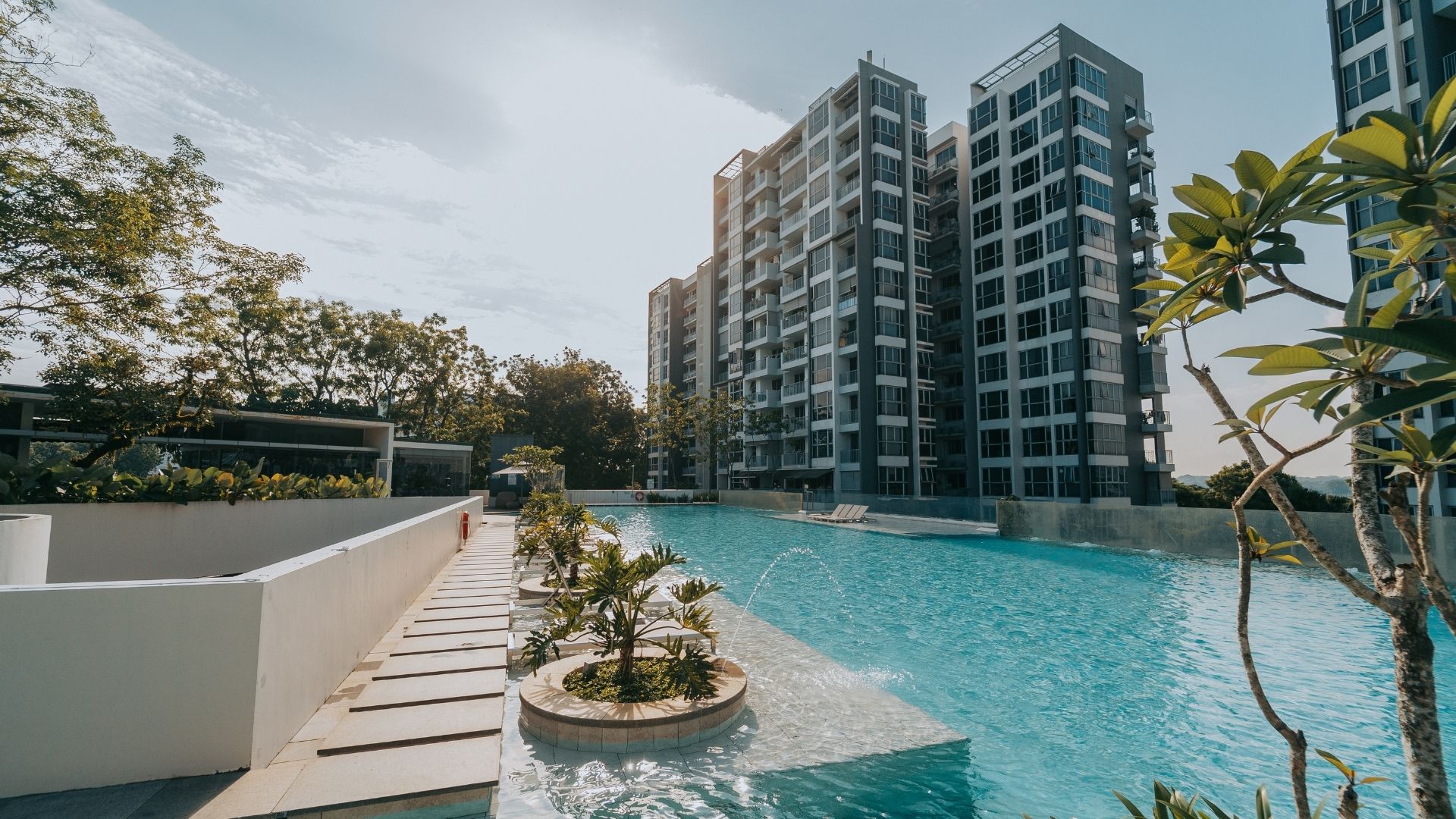 The landscaped walkway of the swimming pool area at The Estuary Condominium. Water fountain features splash back into the 50-metre lap pool.