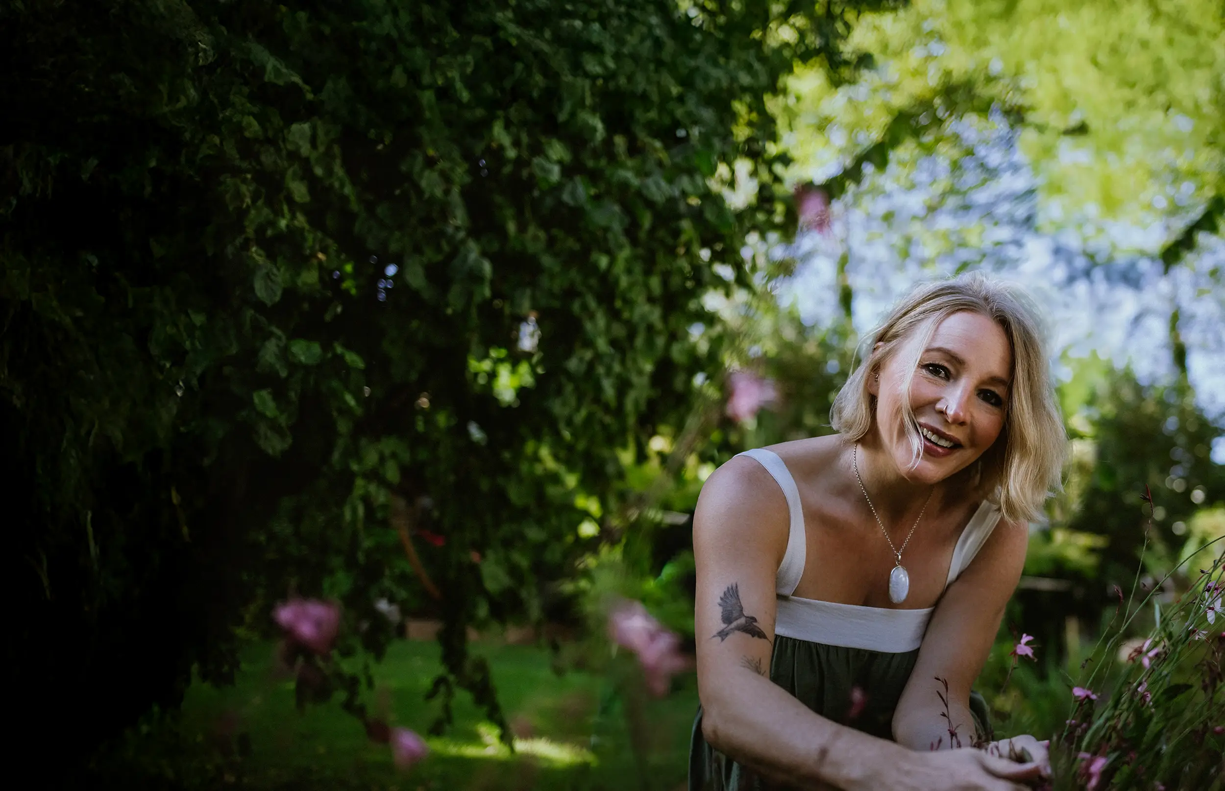 Annette Burger, die Inhaberin von »Dein Glücksgarten« kniet vor einem Meer an Blumen in einem wunderschön angelegten Garten