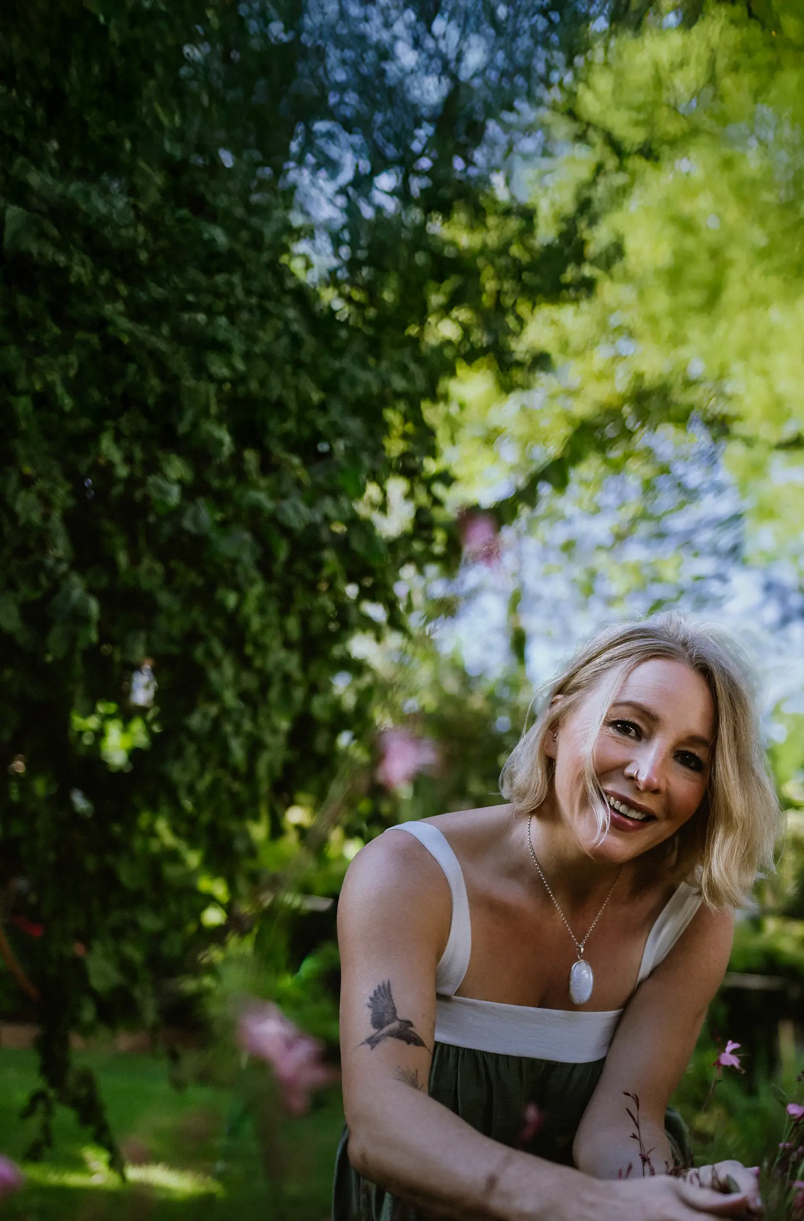 Annette Burger, die Inhaberin von »Dein Glücksgarten« kniet vor einem Meer an Blumen in einem wunderschön angelegten Garten