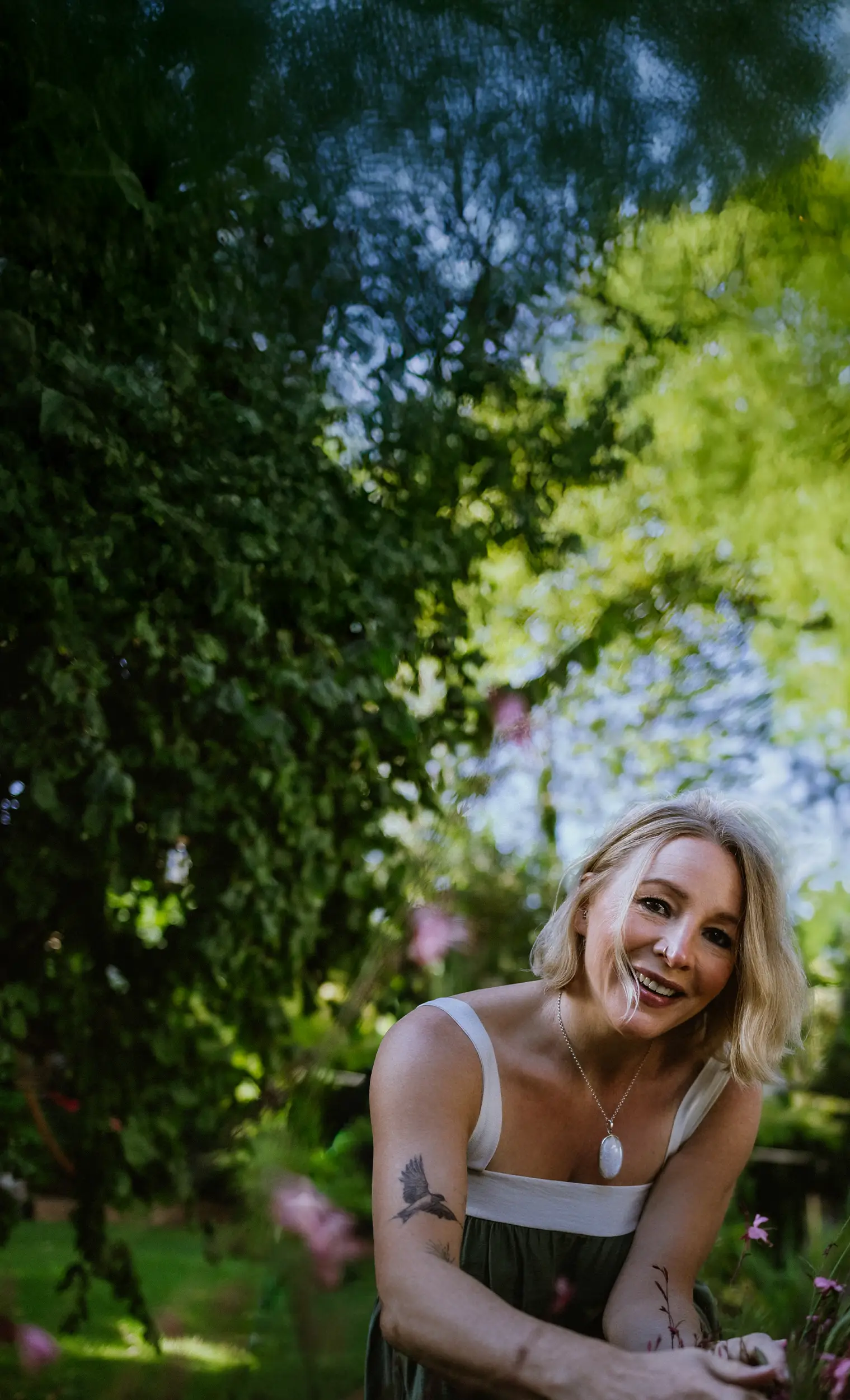 Annette Burger, die Inhaberin von »Dein Glücksgarten« kniet vor einem Meer an Blumen in einem wunderschön angelegten Garten