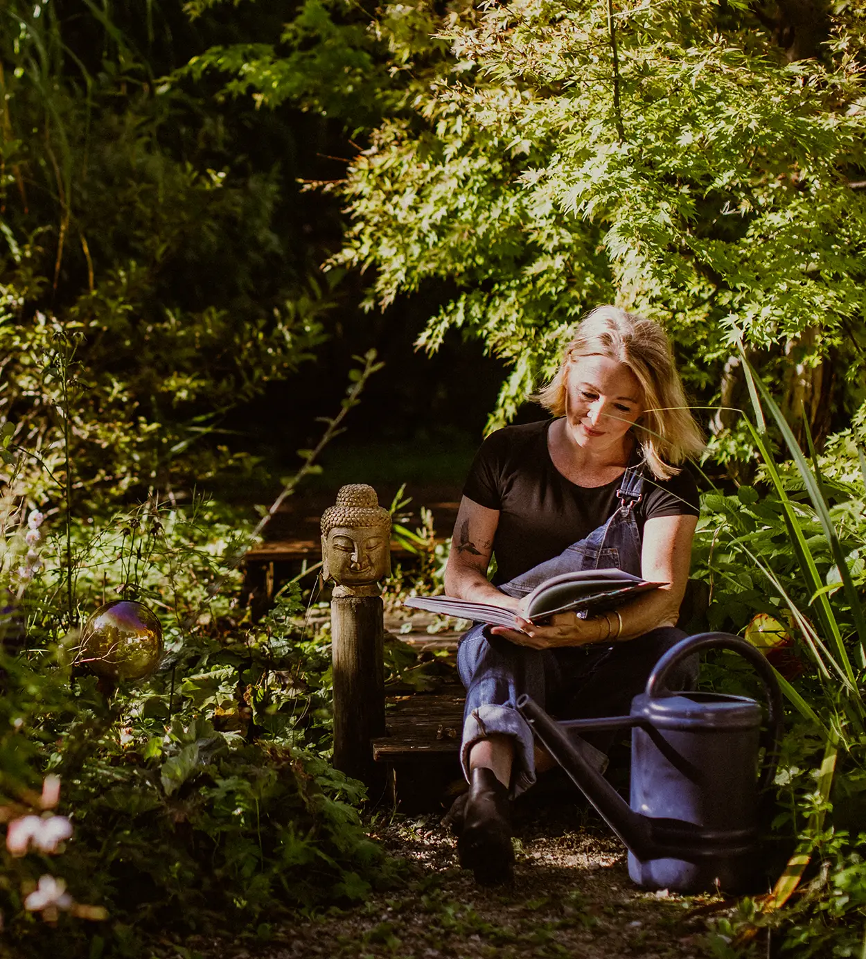 Gartenplanerin Annette Burger sitzt in einem von ihr traumhaft schön gestalteten Garten und ist in ein Buch vertieft