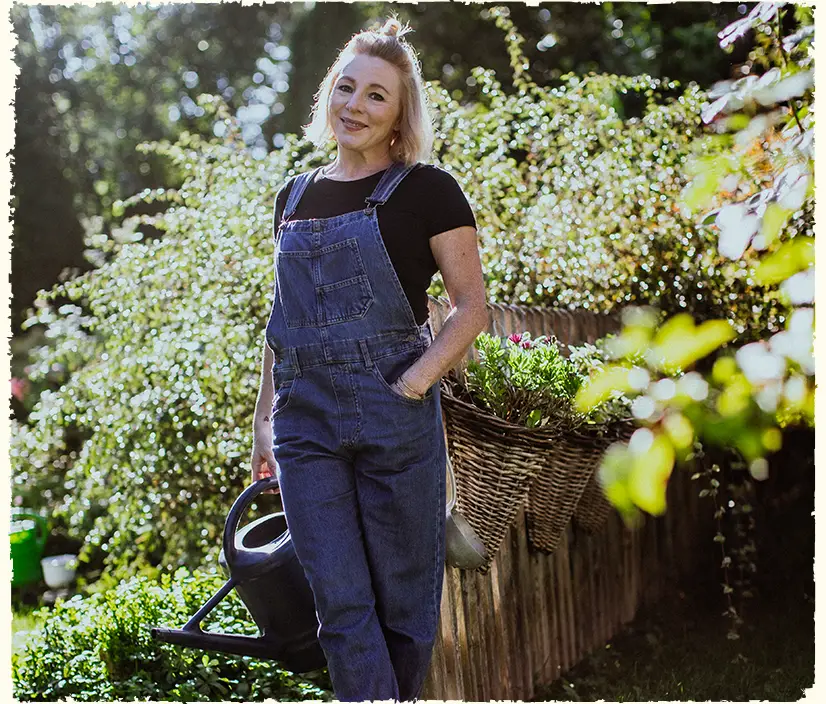 Annette Burger, die Inhaberin von »Dein Glücksgarten« steht in einem von ihr geplanten Garten vor einem Holzzaun