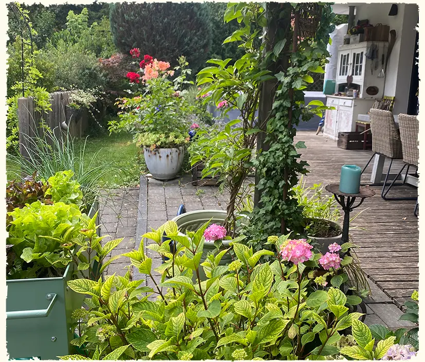 Liebevoll gestaltete Pflanzendeko entlang einer Holzterrasse zeigt die Handschrift von Gartendesignerin Annette Burger