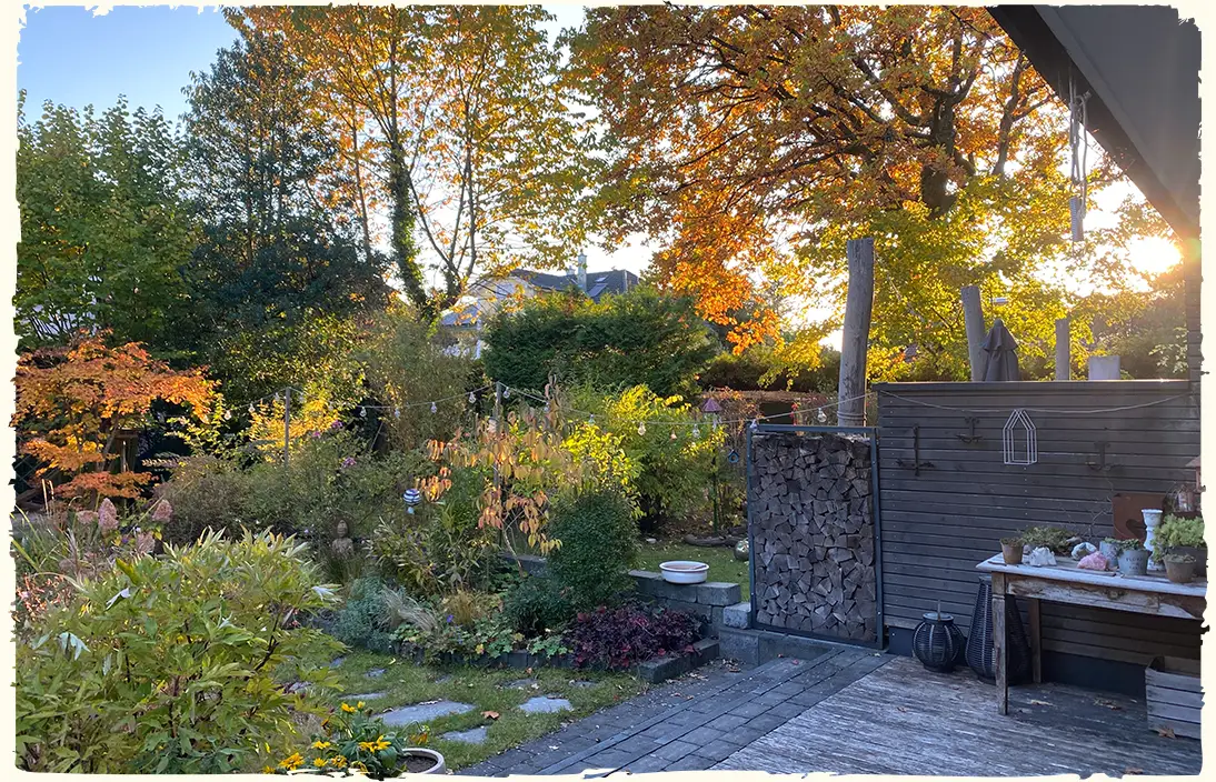 Blick von der Terrasse auf die prachtvolle Herbstfärbung von Stauden und Bäumen