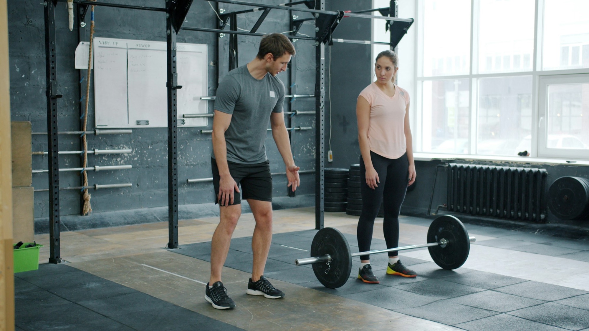 A trainer coaching a client through a barbell lift