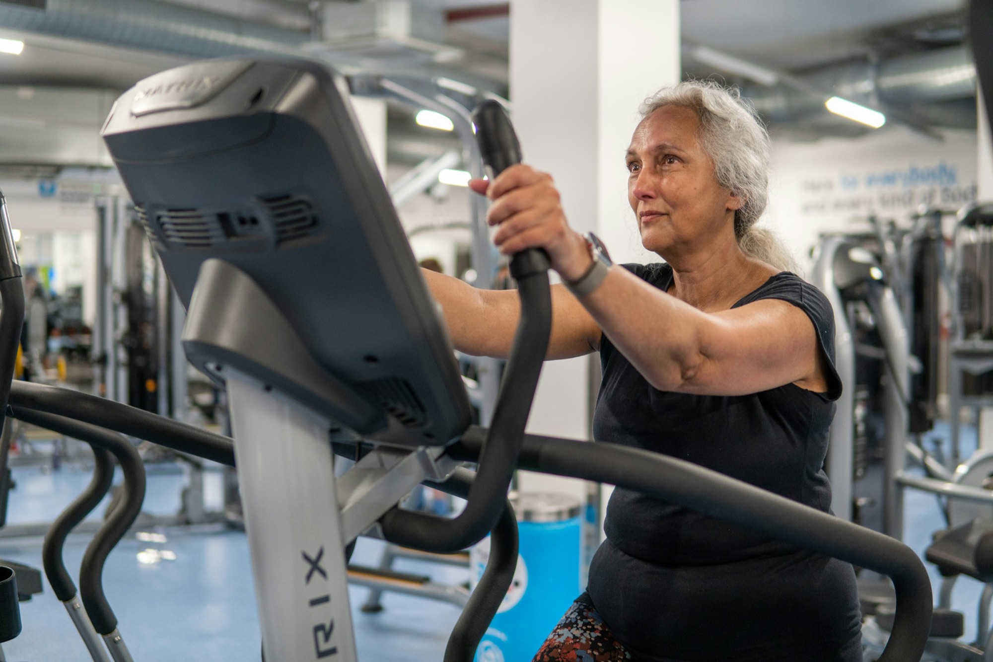 A midlife woman training on equipment in a bright gym