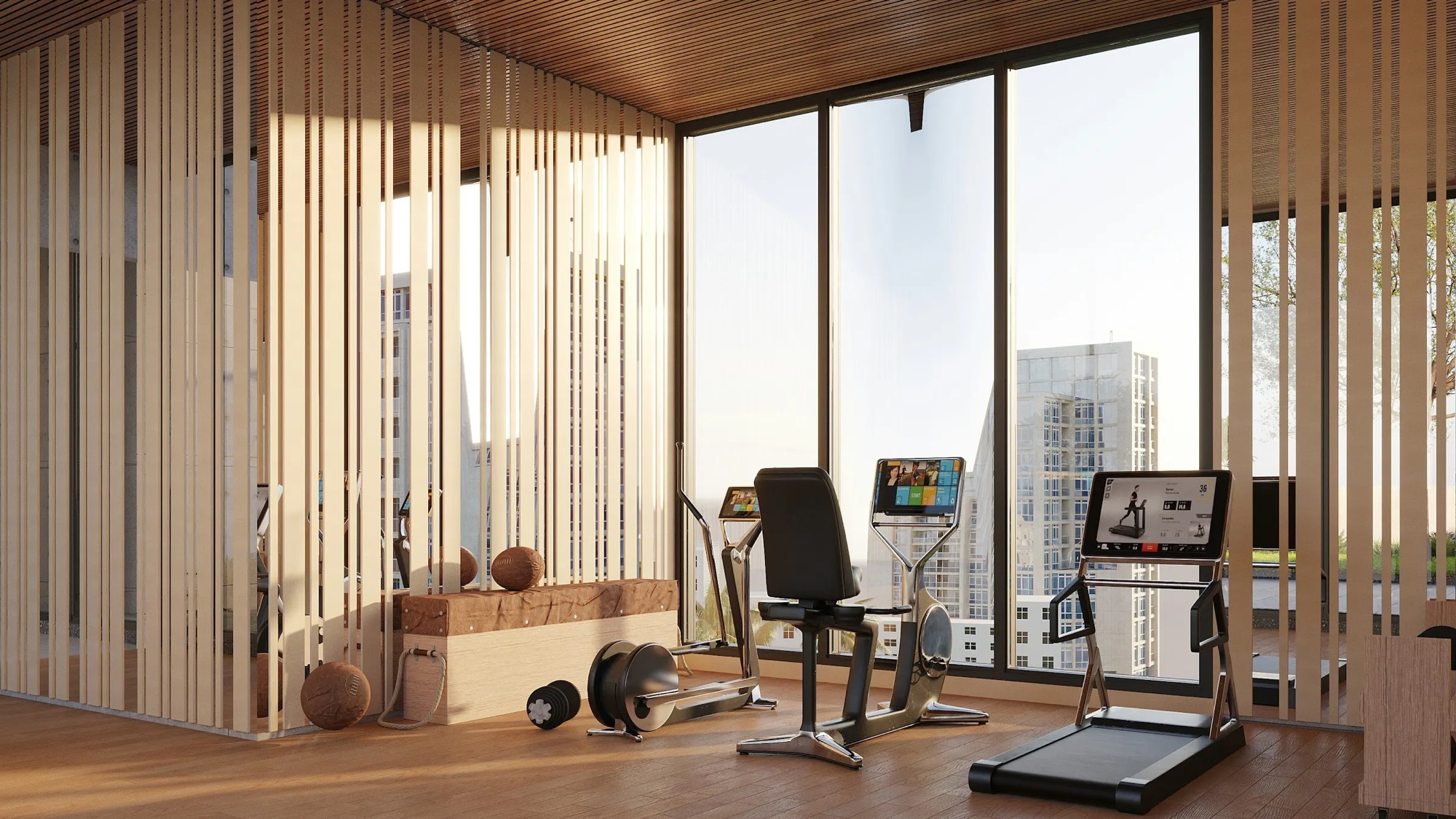 A sunlit residents' fitness center with floor to ceiling windows