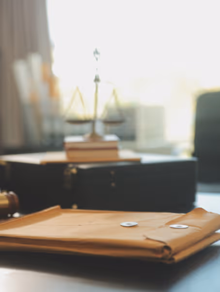 Une grande enveloppe en papier brun sur un bureau avec une balance de la justice floue en arrière-plan.