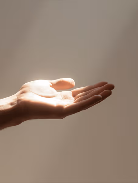 Main humaine ouverte et éclairée par une lumière chaude sur un fond neutre.