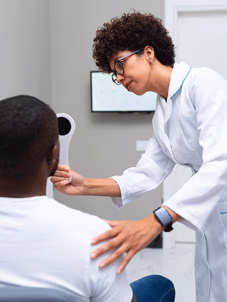 Une professionnelle de santé en blouse blanche examine l'œil d'un patient avec un occludeur.