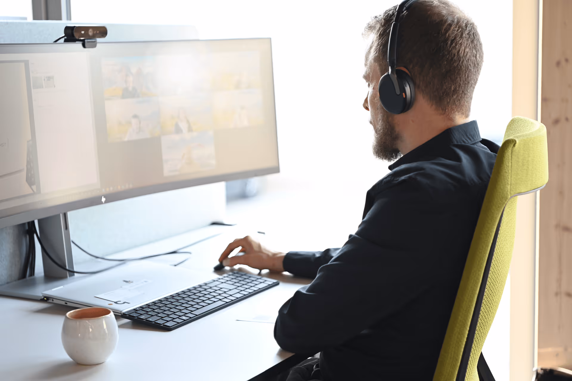 Mitarbeiter mit Headset in einer Microsoft-Teams-Videokonferenz am Bildschirm