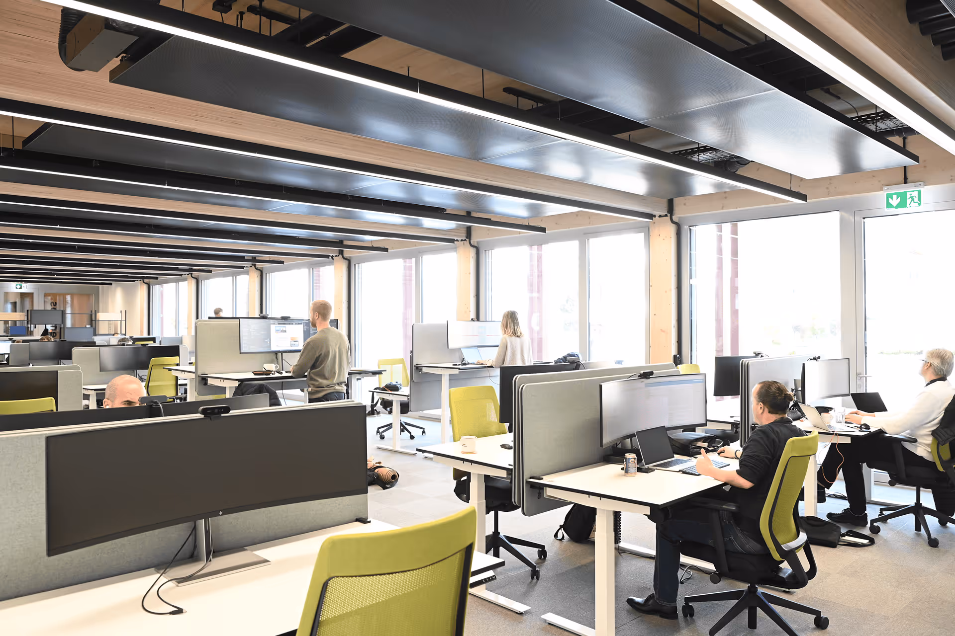 Modernes Holzbau-Grossraumbüro mit höhenverstellbaren Schreibtischen und mehreren Arbeitsplätzen
