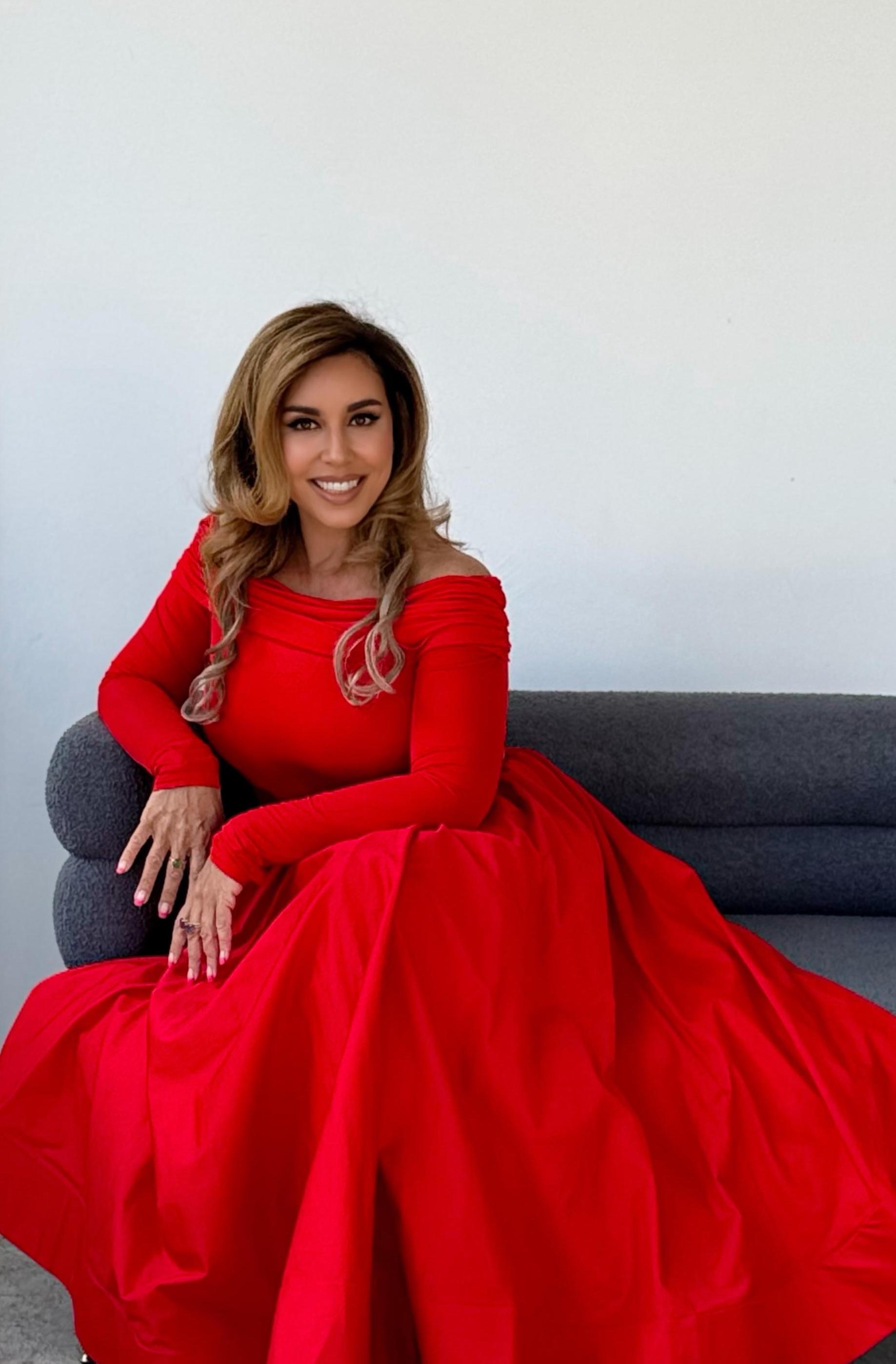 Maria Micha seated in a red dress, representing therapy for feeling stuck in life.