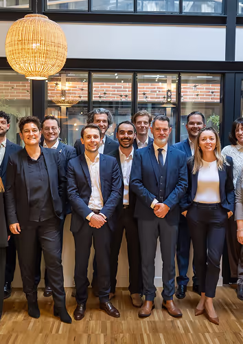 Groupe de professionnels d'Osmose posant en tenue formelle dans un bureau moderne avec des fenêtres en verre et une décoration végétale.