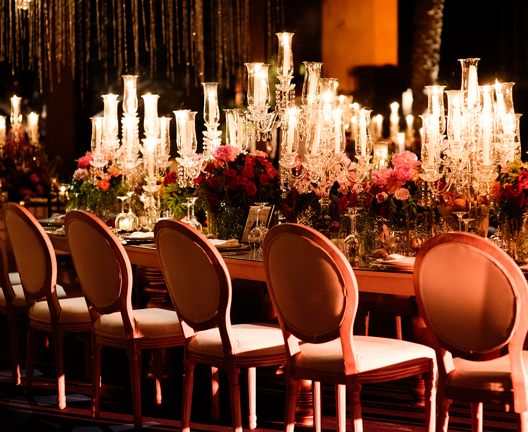 Bride and groom holding hands at an outdoor wedding altar adorned with abundant white flowers and surrounded by bridesmaids and groomsmen.