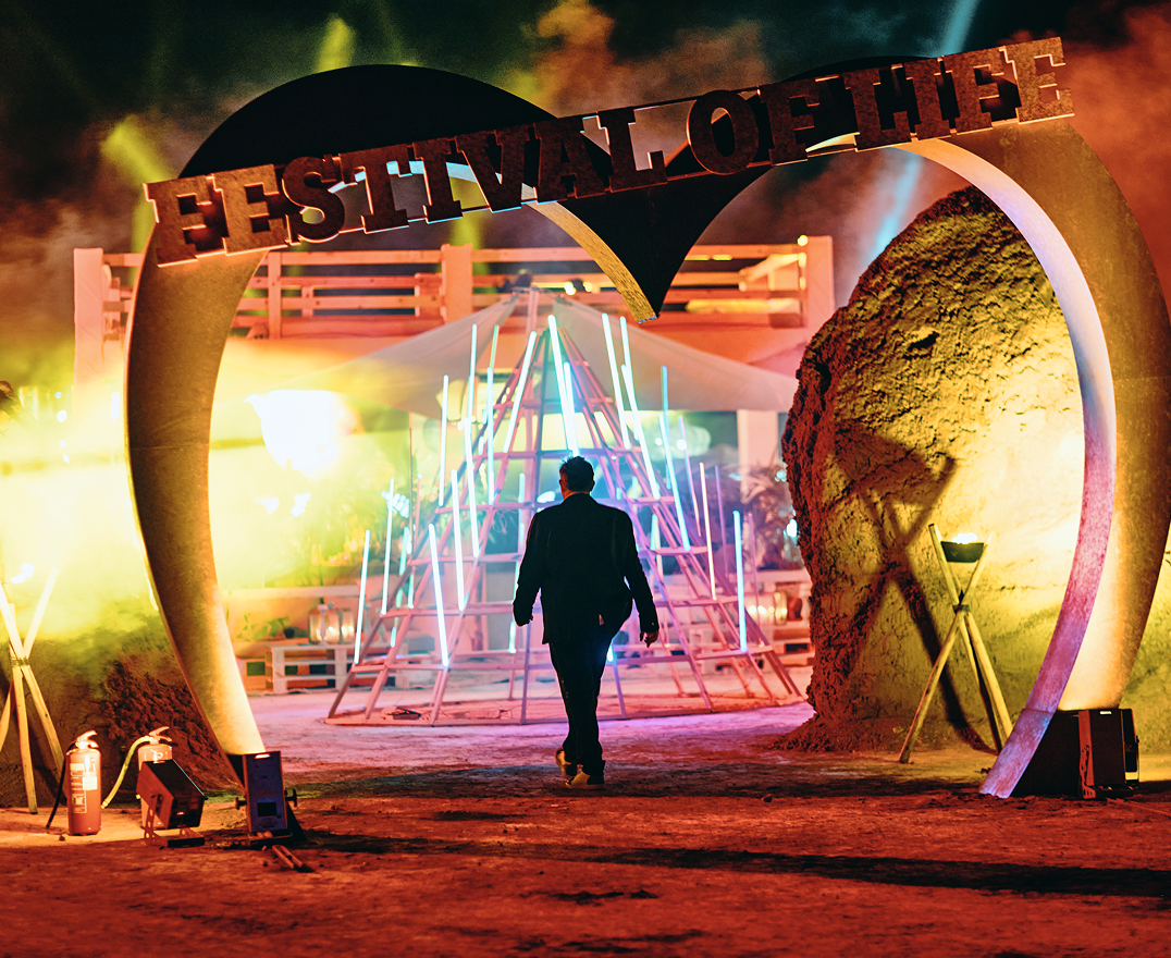 Bride and groom holding hands at an outdoor wedding altar adorned with abundant white flowers and surrounded by bridesmaids and groomsmen.