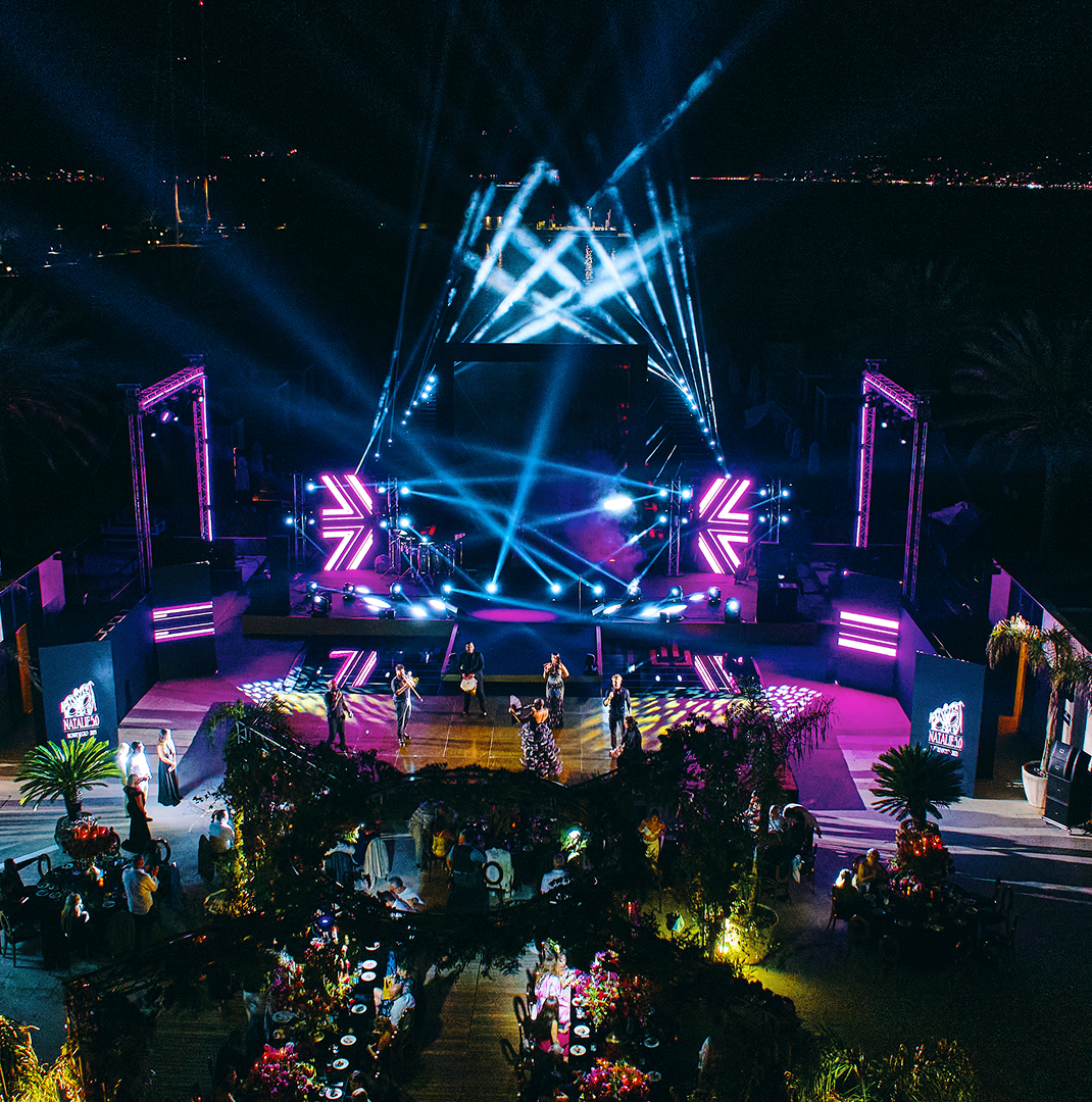 Outdoor wedding aisle lined with white floral arches and green grass under clear blue sky.
