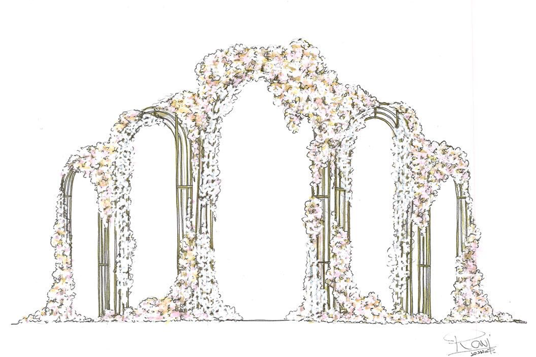 Long table set with white plates, crystal glasses, and decorated with lush green and white floral arrangements for an elegant event.