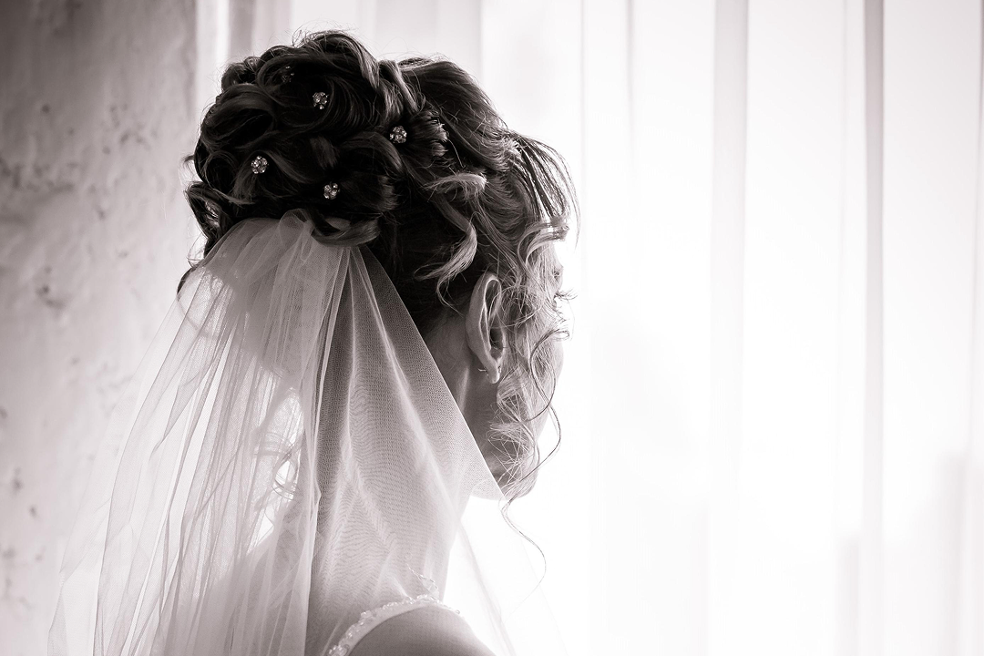 Long table set with white plates, crystal glasses, and decorated with lush green and white floral arrangements for an elegant event.