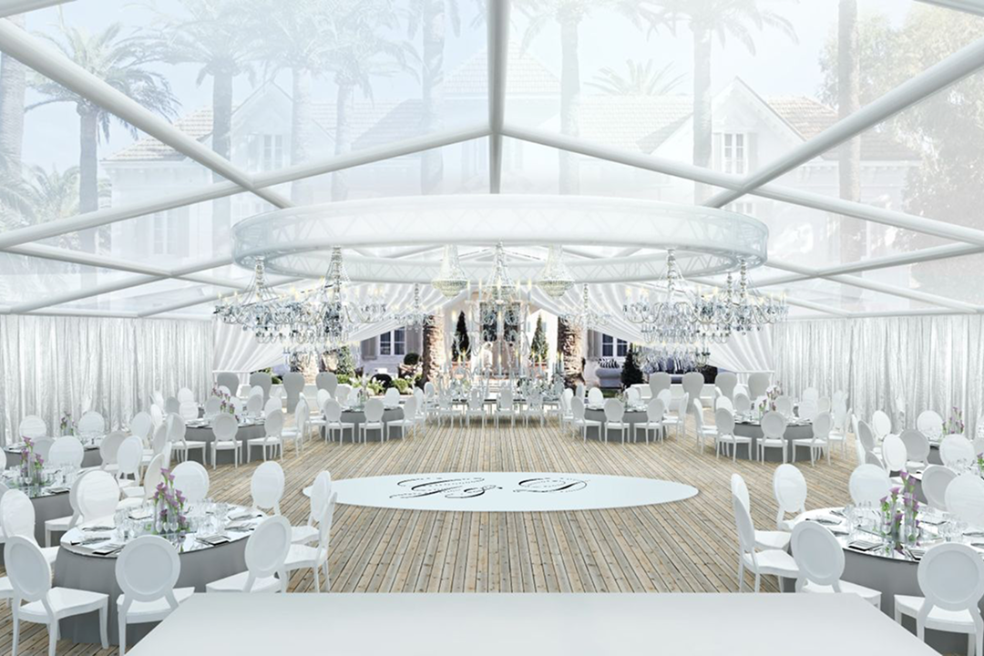 Outdoor wedding aisle decorated with white and pink floral arrangements and a flower-covered arch under a clear blue sky.