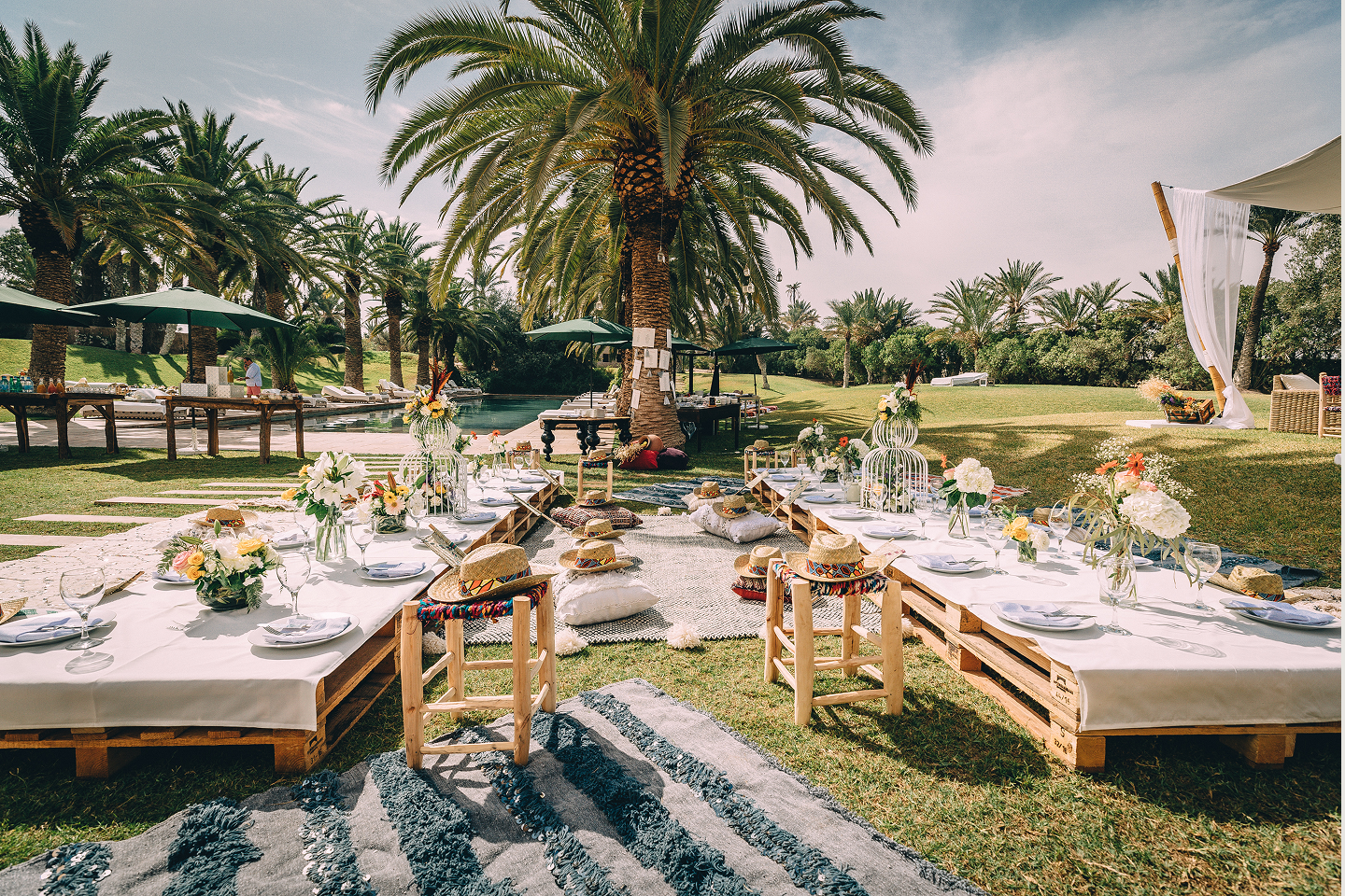 Long table set with white plates, crystal glasses, and decorated with lush green and white floral arrangements for an elegant event.