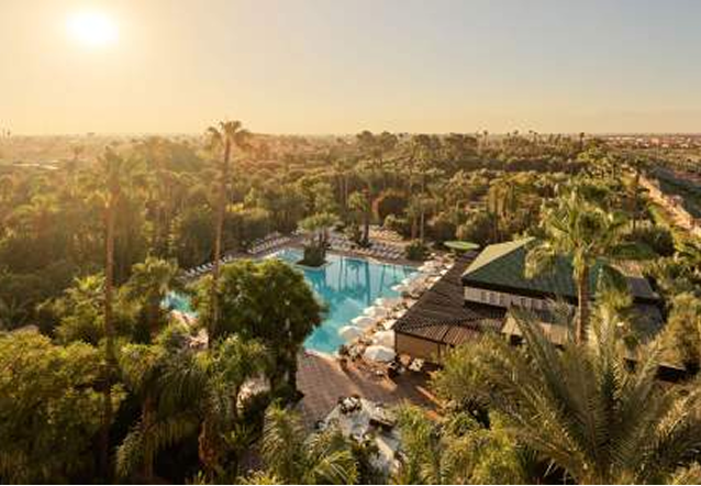 Elegant outdoor event with guests dining beside a large historic white building with ornate windows and greenery.