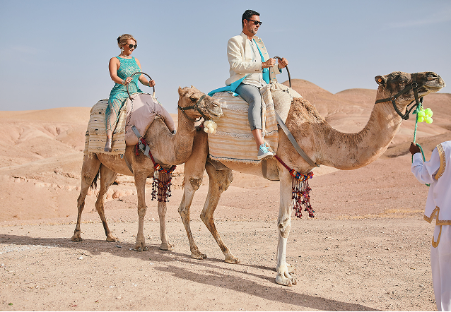 Elegant outdoor event with guests dining beside a large historic white building with ornate windows and greenery.