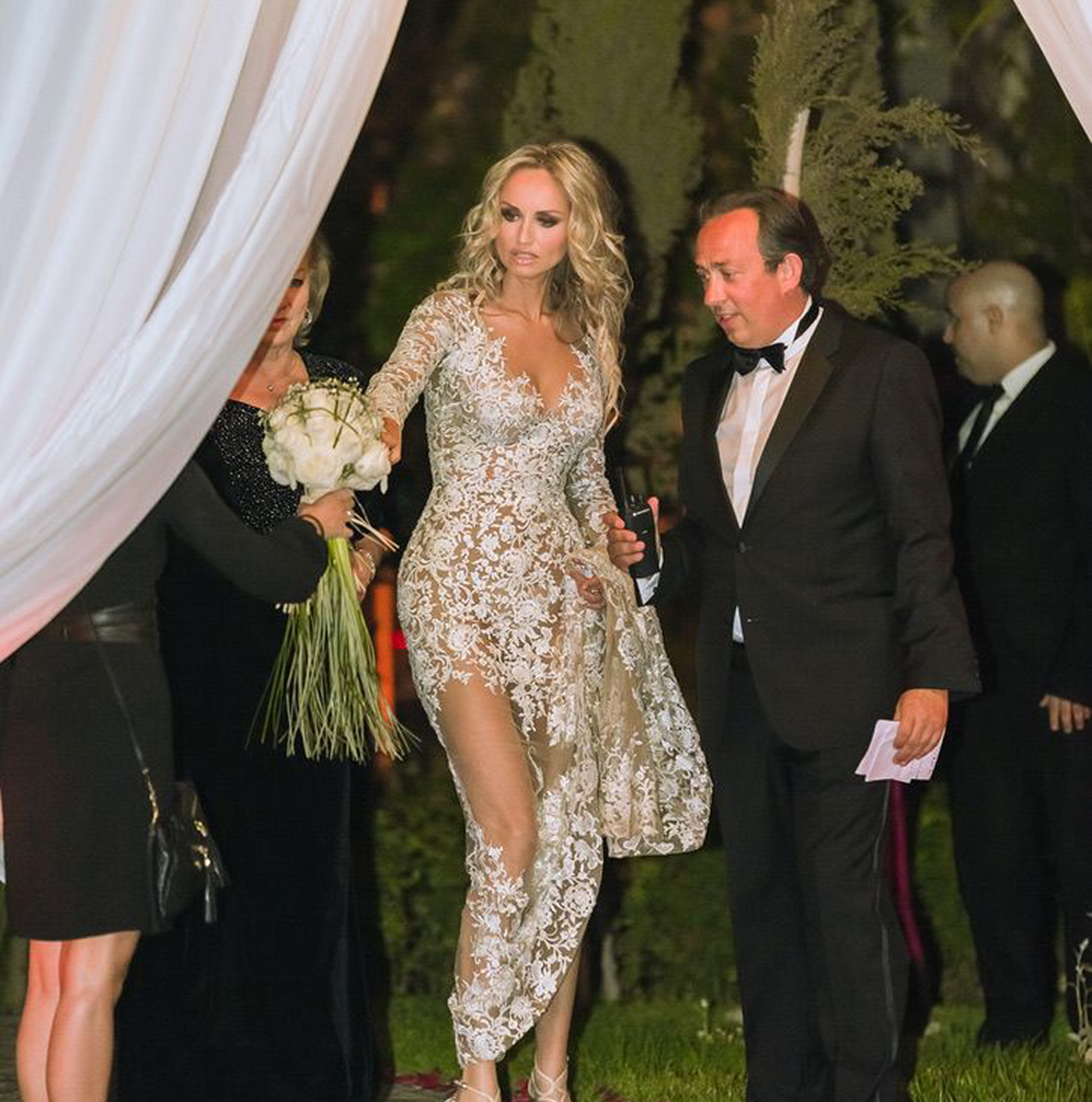Sunlight shining through hanging white flowers and green leaves in an outdoor setting.